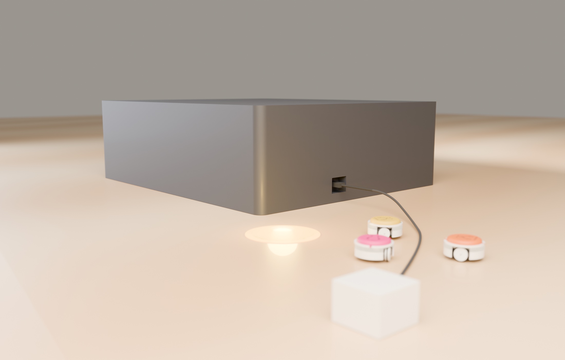The closed case on a table with a USB-C cable running from the port in its end wall to a charger; three bots and a light pad in front.